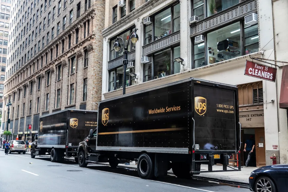 Two brown UPS trucks parked at curbside on New York City street.